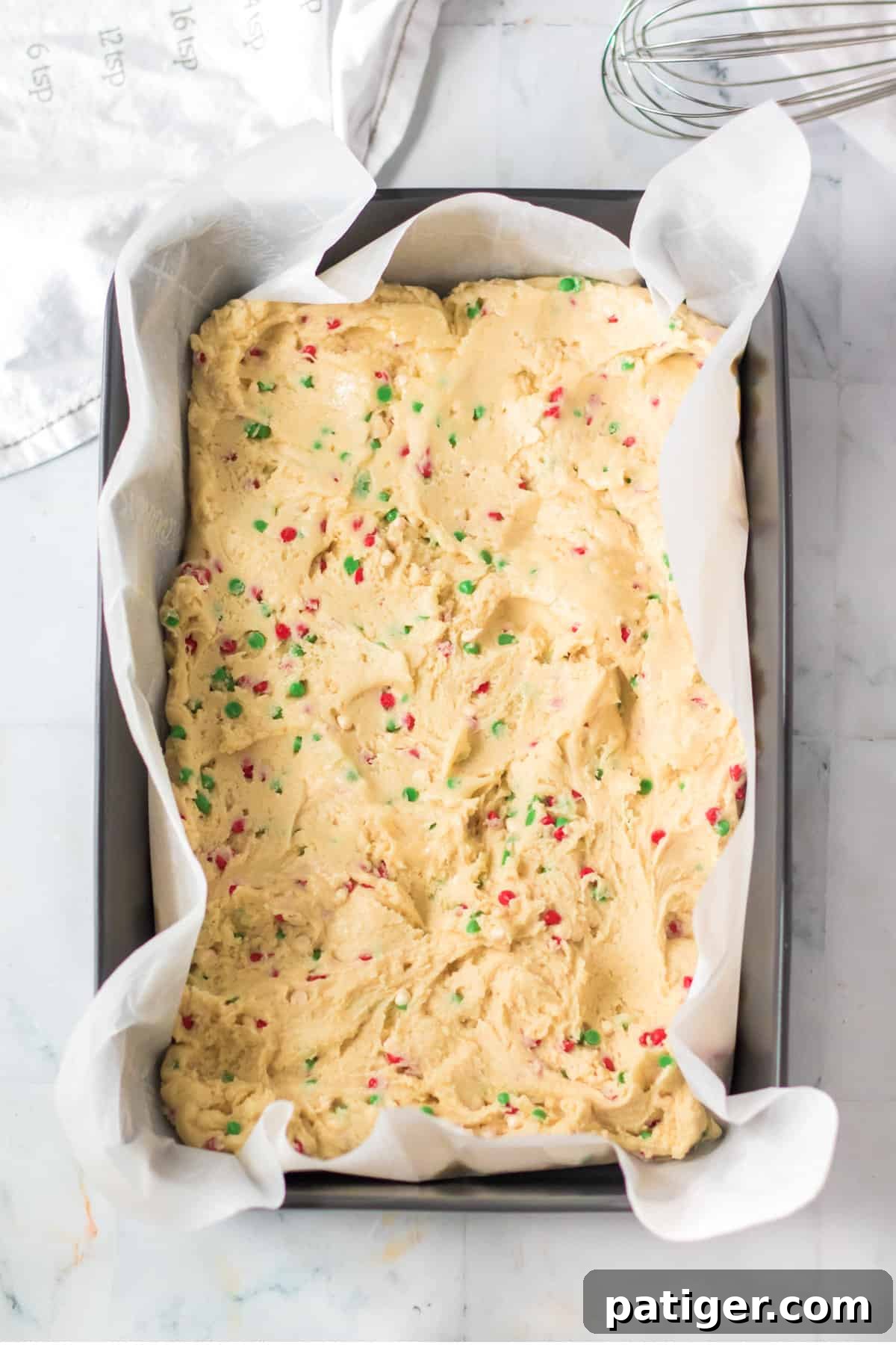 Christmas sugar cookie bar dough pressed into 9 x 13 inch baking pan lined with parchment paper.