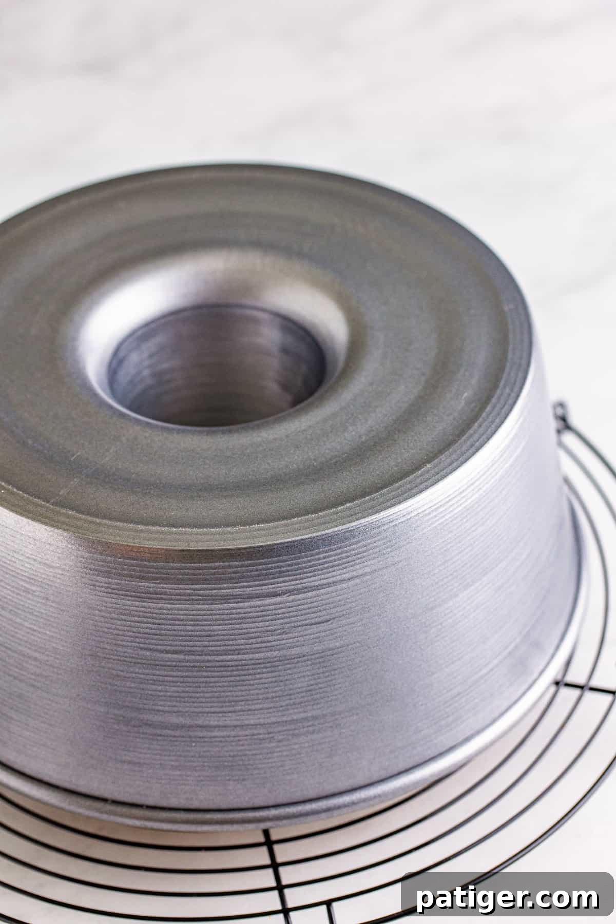 Feather-Light Angel Food Dream 11 An angel food cake pan positioned upside down on a cooling rack, a vital step to prevent the cake from collapsing after baking.