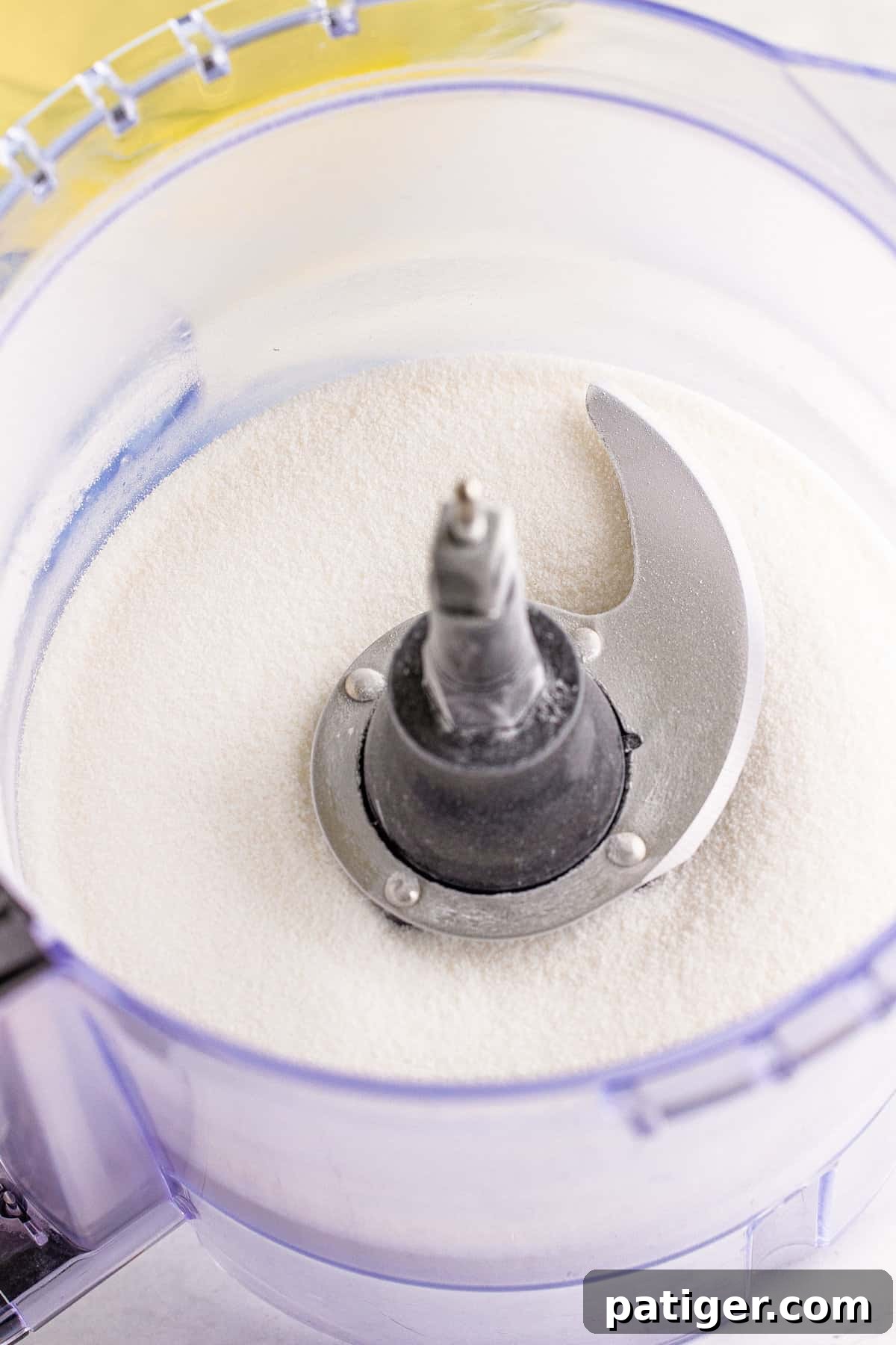Feather-Light Angel Food Dream 5 Close-up of granulated sugar being processed into a superfine powder in a food processor, ready for angel food cake preparation.