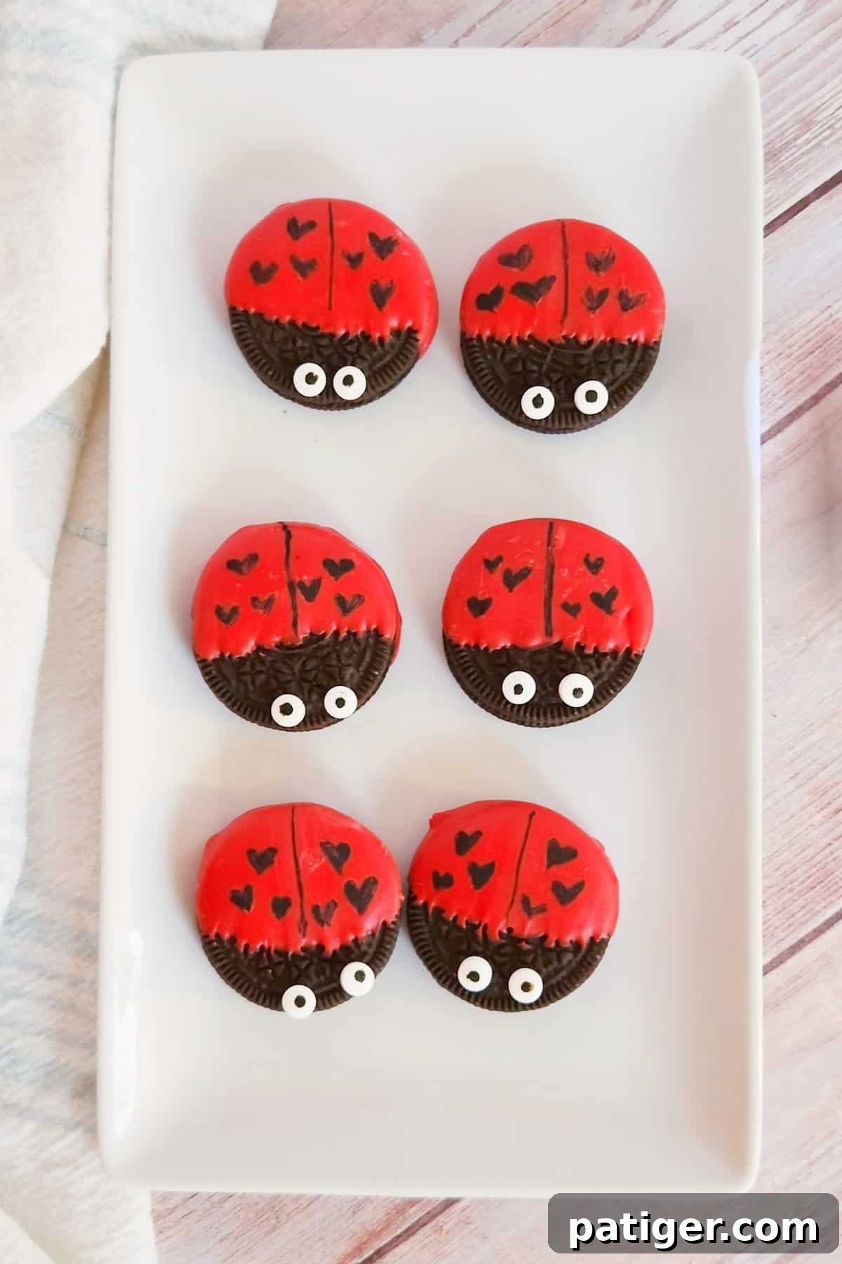 Oreo cookies dipped in red chocolate and decorated to look like ladybugs with heart spots for Valentine's Day.