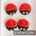 Oreo cookies dipped in red chocolate and decorated to look like ladybugs with heart spots for Valentine's Day.
