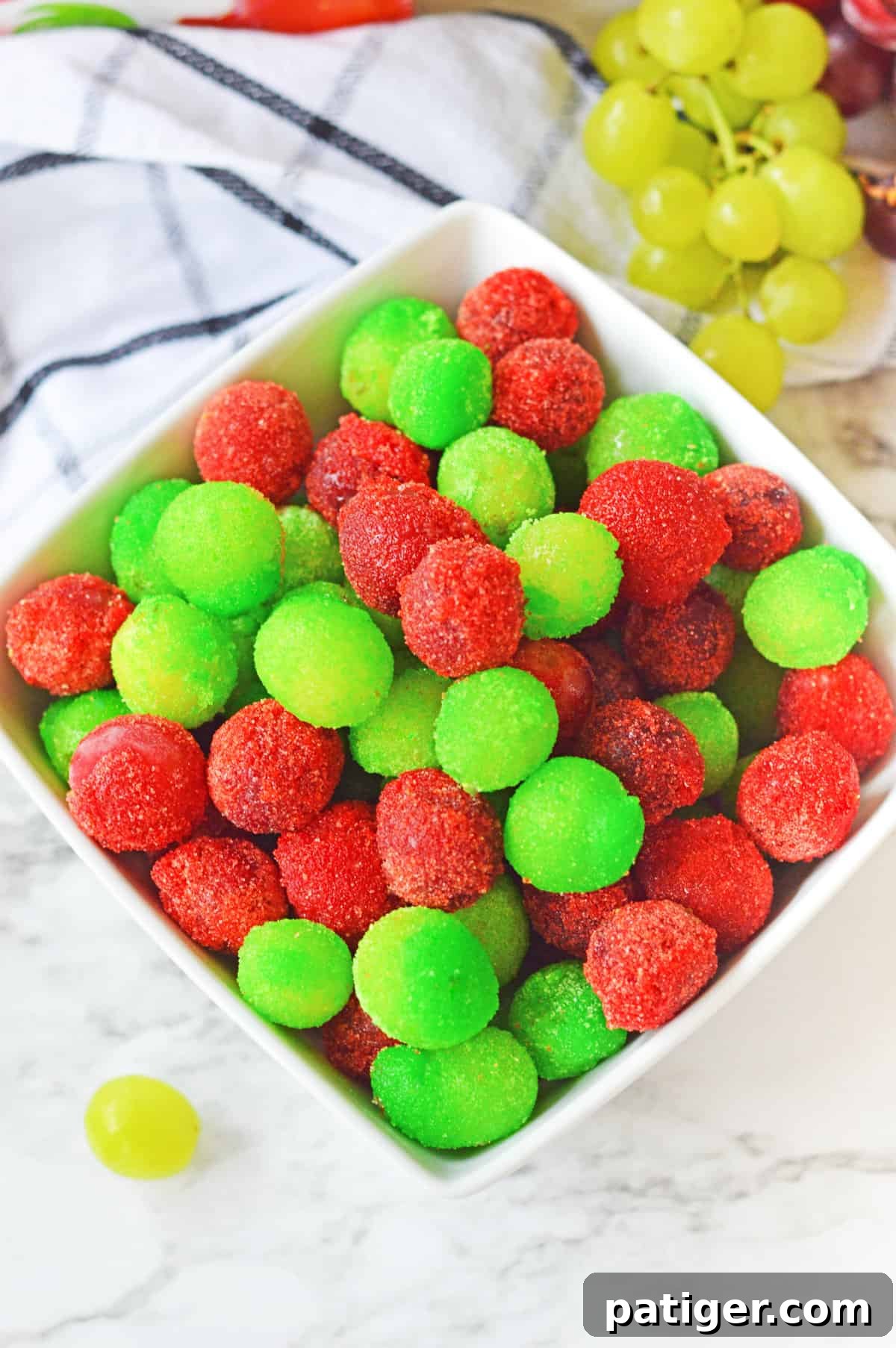 Overhead image of strawberry and green apple candied grapes in a white bowl.