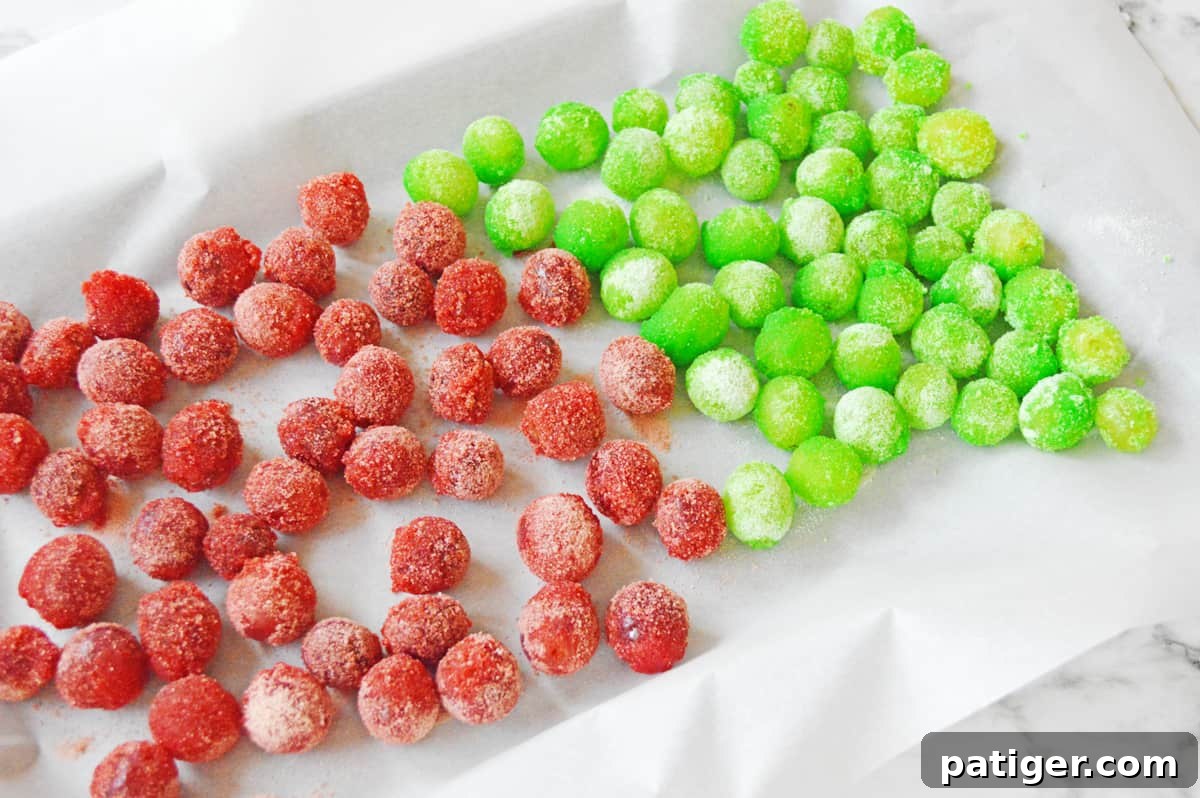 Red and green frozen jello grapes on lines baking sheet.