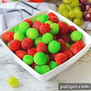 Candied grapes made with red and green jello powder in a white bowl.