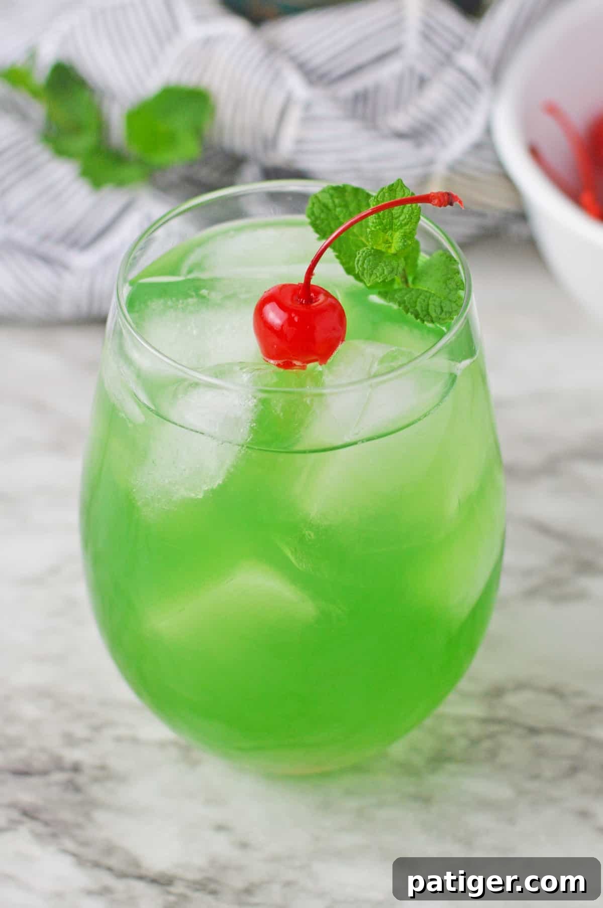 Emerald Isle Elixir 2 Vibrant green Luck of the Irish cocktail garnished with a maraschino cherry and fresh mint sprig, perfect for St. Patrick's Day.