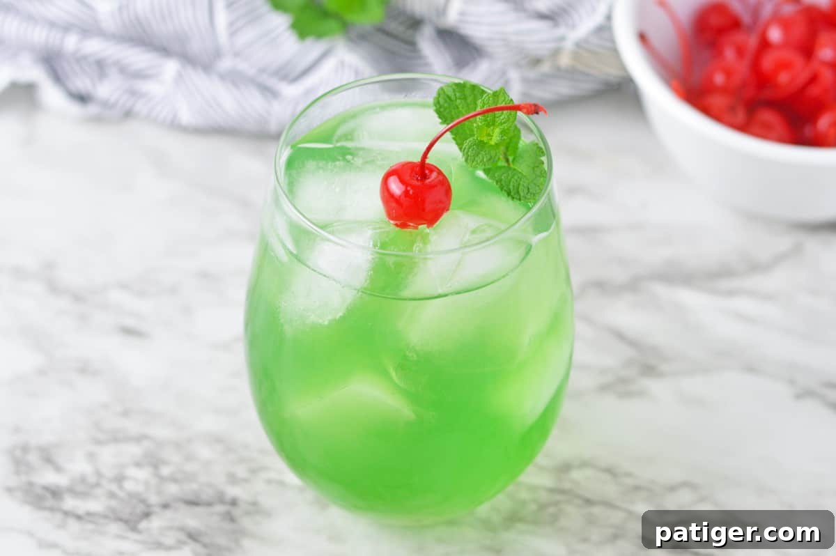 Emerald Isle Elixir 5 A refreshing green drink, the Luck of the Irish cocktail, adorned with a red cherry and a green mint sprig.