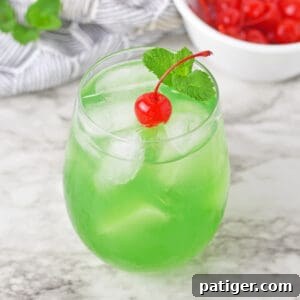 Luck of the Irish green cocktail topped with a cherry and sprig or mint.