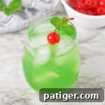 Luck of the Irish green cocktail topped with a cherry and sprig or mint.