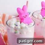 Vibrant Easter Elixir 11 Easter Punch topped with mini marshmallows, confetti-style sprinkles, pink marshmallow Peeps, and a pink and white paper straw.