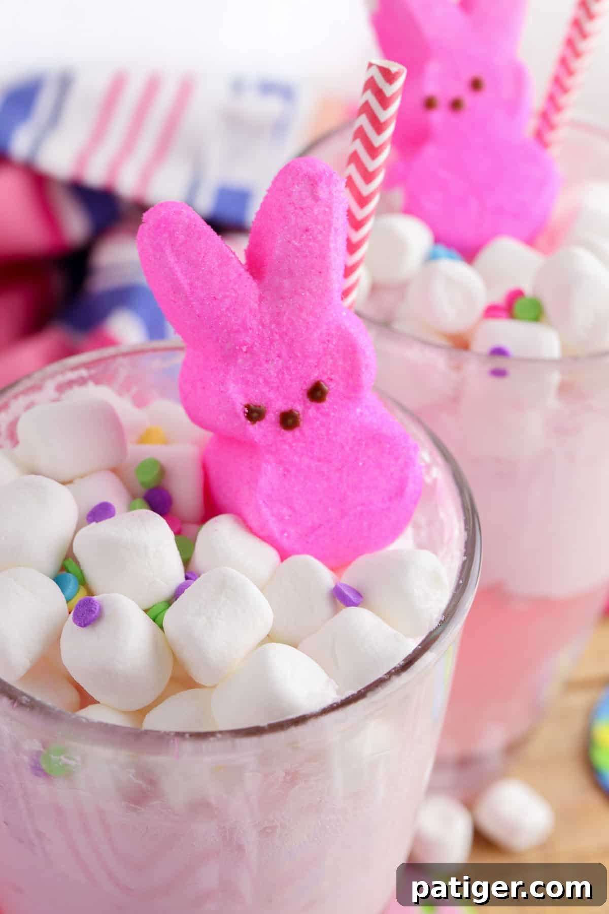 Vibrant Easter Elixir 3 Close-up of two glasses filled with a pink Easter punch, artfully garnished with mini marshmallows, colorful sprinkles, and cheerful pink Peeps bunny candies.