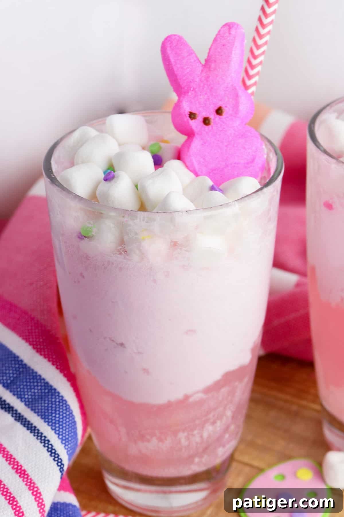 Vibrant Easter Elixir 8 A refreshing glass of pink Easter Bunny Punch, showcasing layers of strawberry ice cream, fizzy soda, and sweet fruit juice, beautifully crowned with mini marshmallows and a whimsical Peeps bunny.