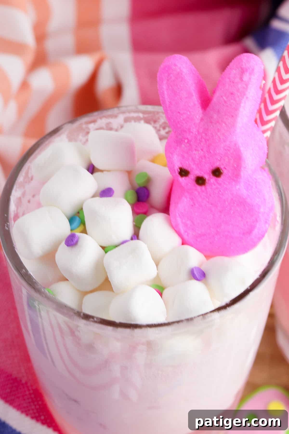 Vibrant Easter Elixir 9 A close-up of a glass of pink Peeps punch, generously topped with fluffy mini marshmallows, a charming pink Peeps bunny, and vibrant sprinkles for a festive Easter drink.