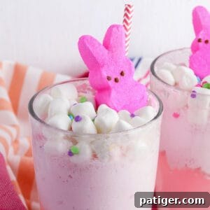 Vibrant Easter Elixir 10 Easter Punch topped with mini marshmallows, confetti-style sprinkles, pink marshmallow Peeps, and a pink and white paper straw.