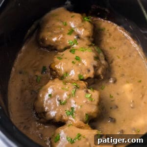 Tender Slow Cooker Salisbury Steaks 11 Slow cooker salisbury steaks smothered with brown gravy and garnished with parsley in a crockpot.