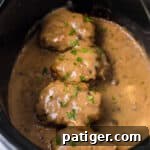 Tender Slow Cooker Salisbury Steaks 12 Slow cooker salisbury steaks smothered with brown gravy and garnished with parsley in a crockpot.