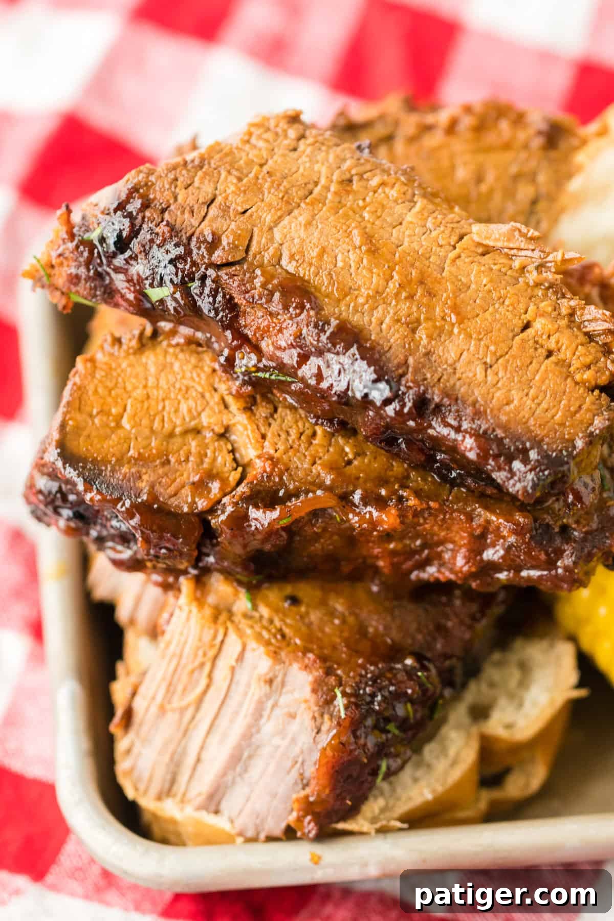 Slices of bbq slow cooked brisket served with corn and bread.