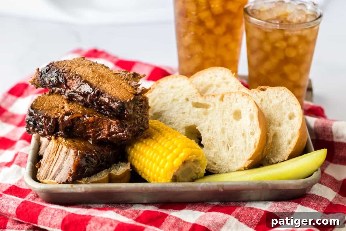 Slow Cooker BBQ Brisket with corn on the cob, bread, pickle, and iced tea.