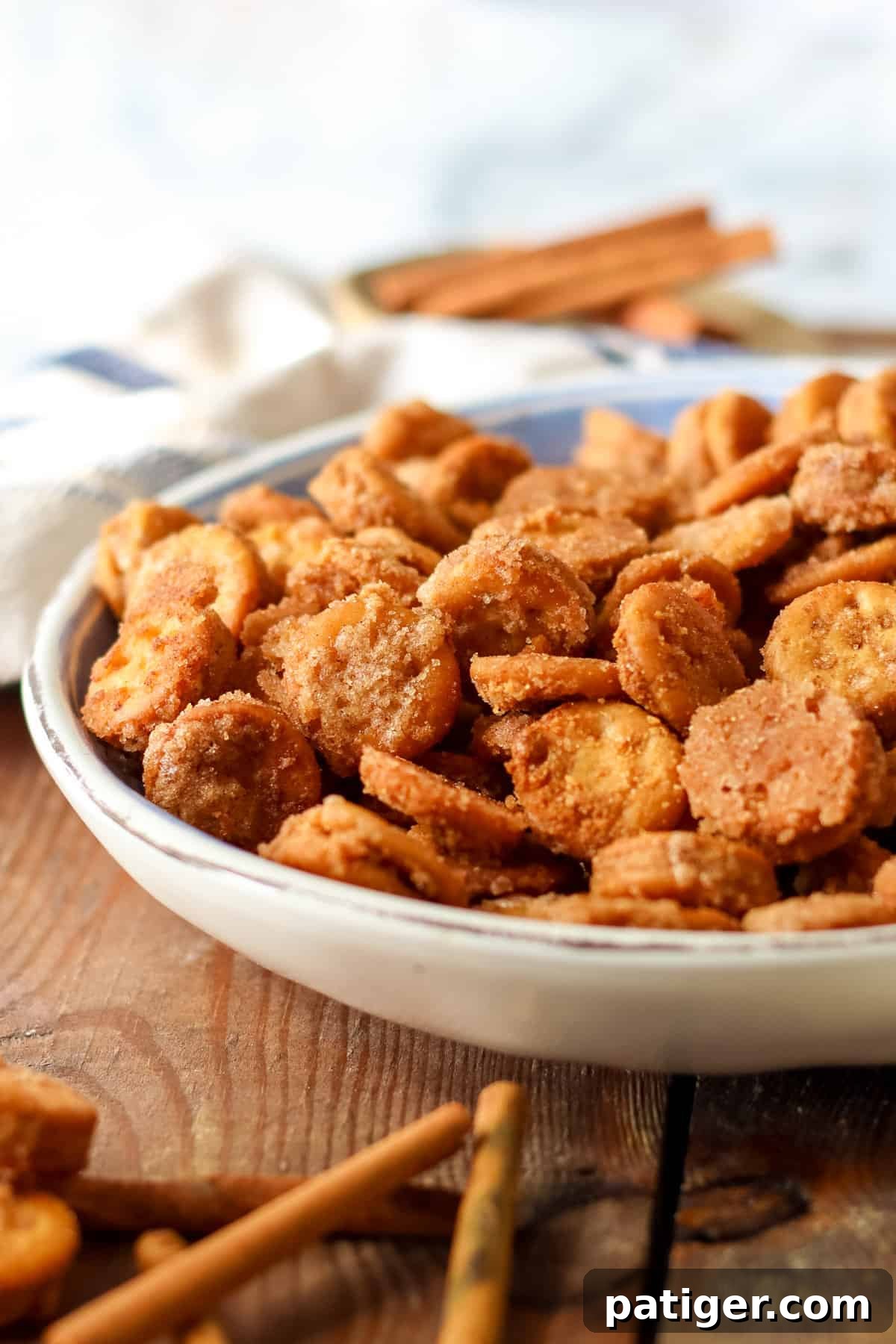 Ritz Cinnamon Churro Bites 6 Side view of a bowl of cinnamon sugar coated Ritz Bits with bowl of cinnamon sugar and cinnamon sticks.