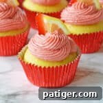 Pink Lemonade Swirl Cupcakes 9 A close-up of a beautifully frosted strawberry lemonade cupcake, with fresh fruit garnishes, ready to be enjoyed.