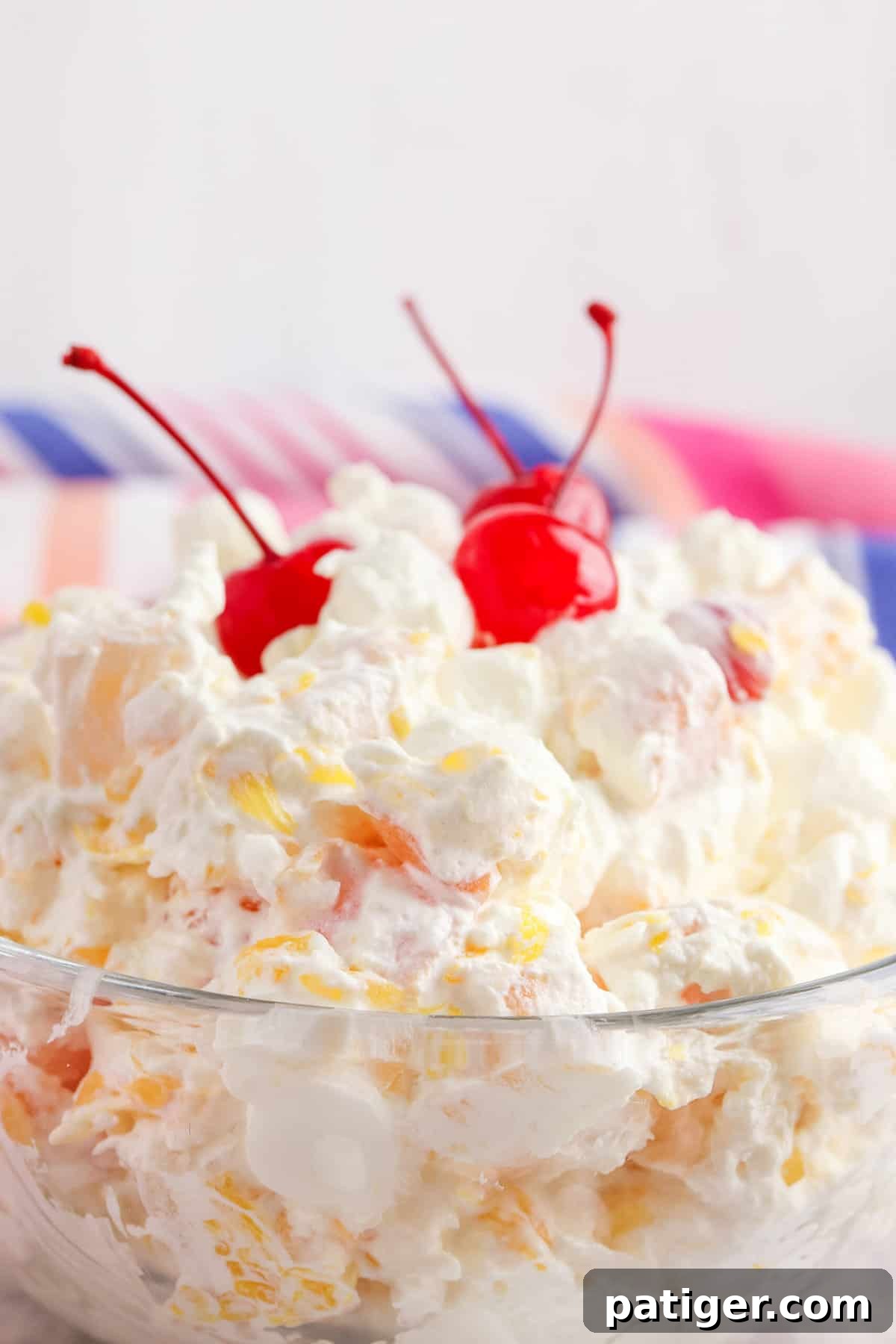 Cloud Nine Fruit Salad 3 Close-up view of creamy marshmallow ambrosia salad topped with three bright maraschino cherries.