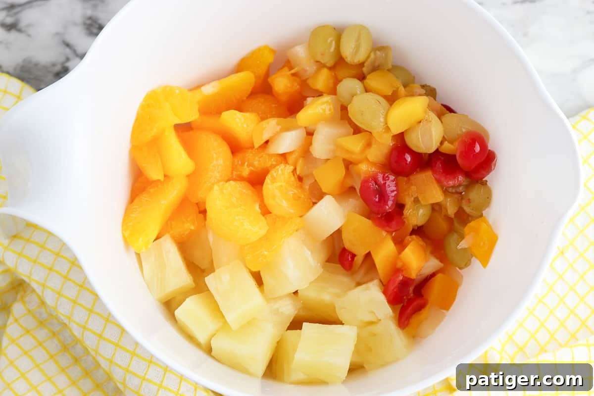 Cloud Nine Fruit Salad 5 Drained canned fruit cocktail, mandarin oranges, and pineapple chunks in a mixing bowl.