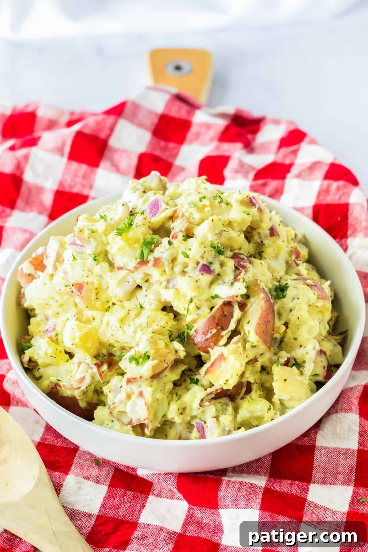 Bowl of red skinned potato salad on a red plaid linen.