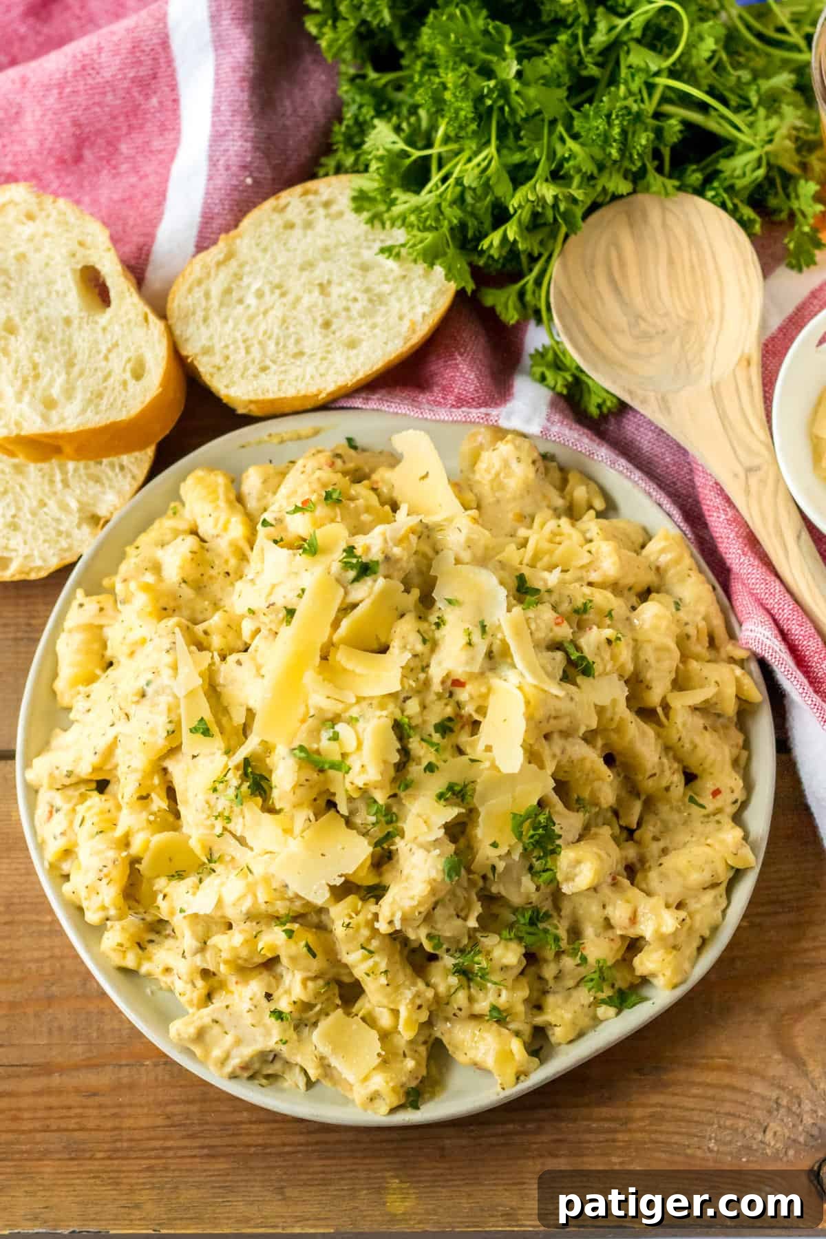 Creamy Crockpot Garlic Parmesan Chicken Pasta 3 Slow Cooker Garlic Parmesan Chicken Pasta served garnished with fresh parsley and with slices or Italian bread on the side.