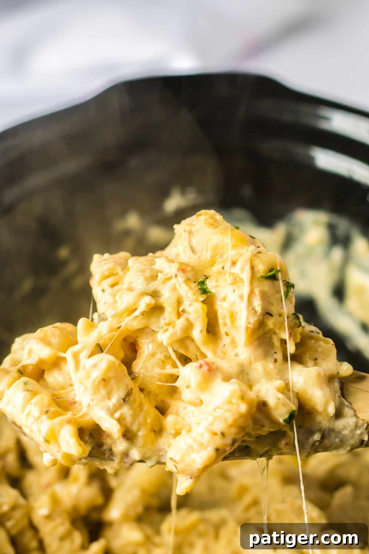 Creamy Crockpot Garlic Parmesan Chicken Pasta 6 Spoon scooping steaming hot bww garlic parmesan chicken pasta out of crockpot.