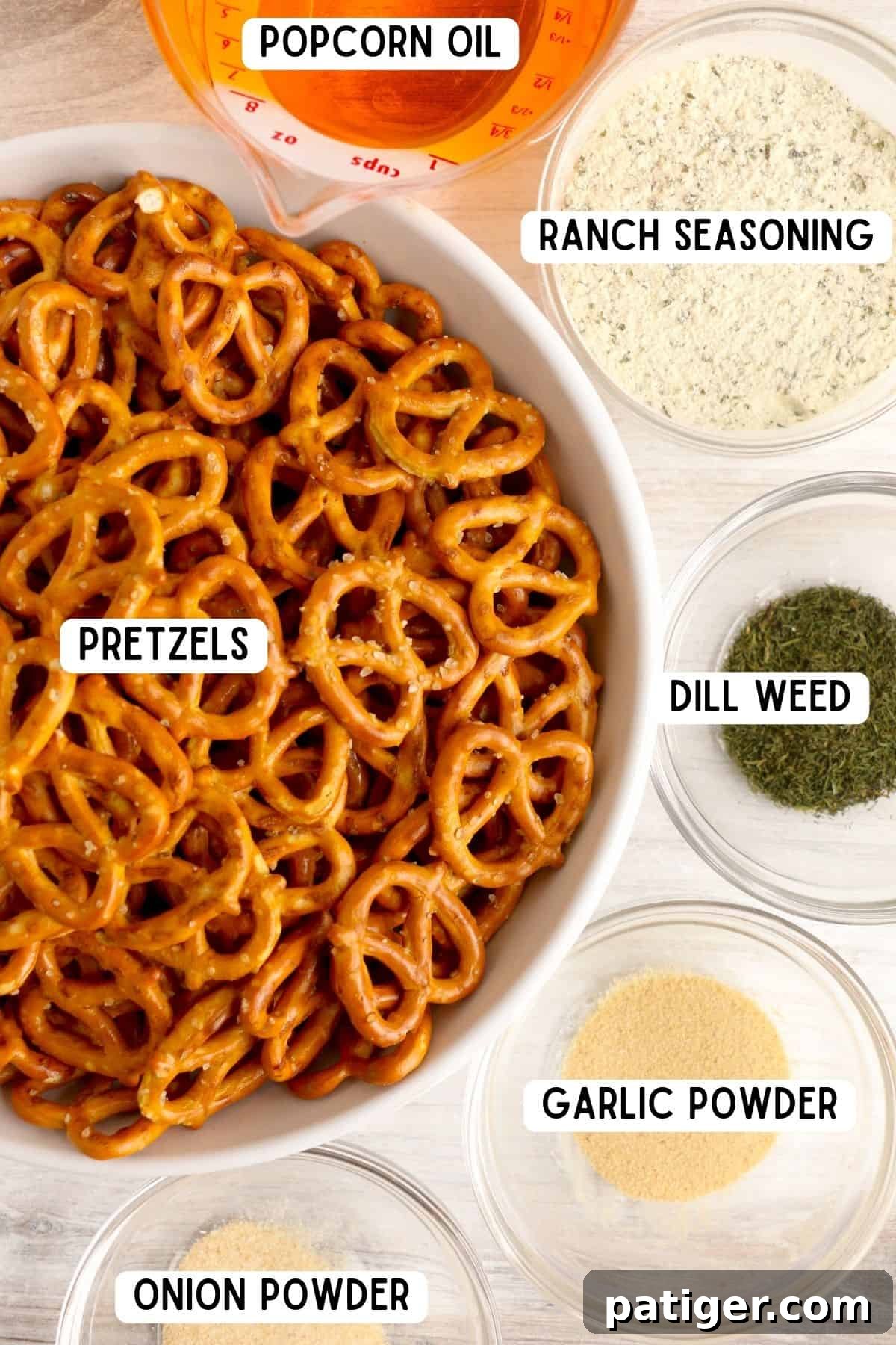 Close-up of ingredients: pretzel twists, popcorn oil, ranch seasoning, garlic powder, dill weed, and onion powder laid out on a surface.