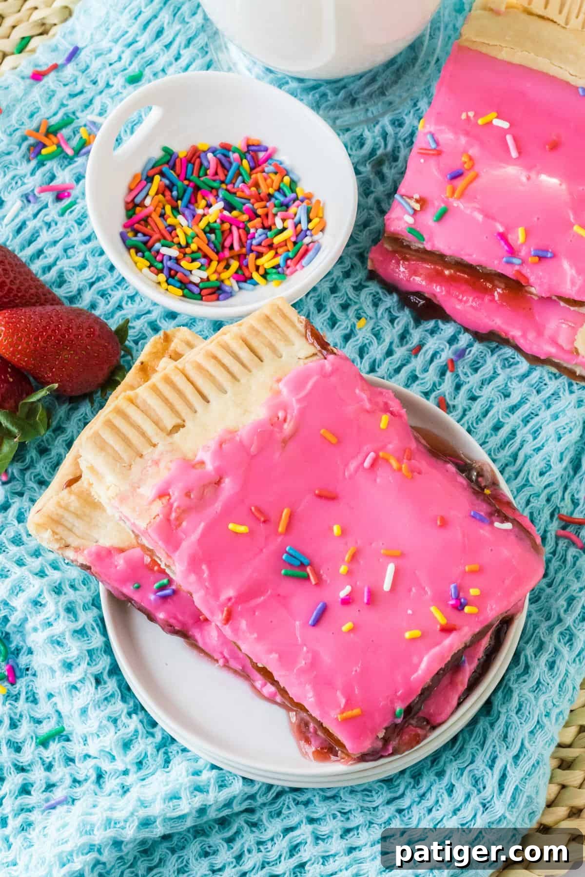 Two large pieces of a giant homemade pop tart on a plate with additional pieces and sprinkles in the background.