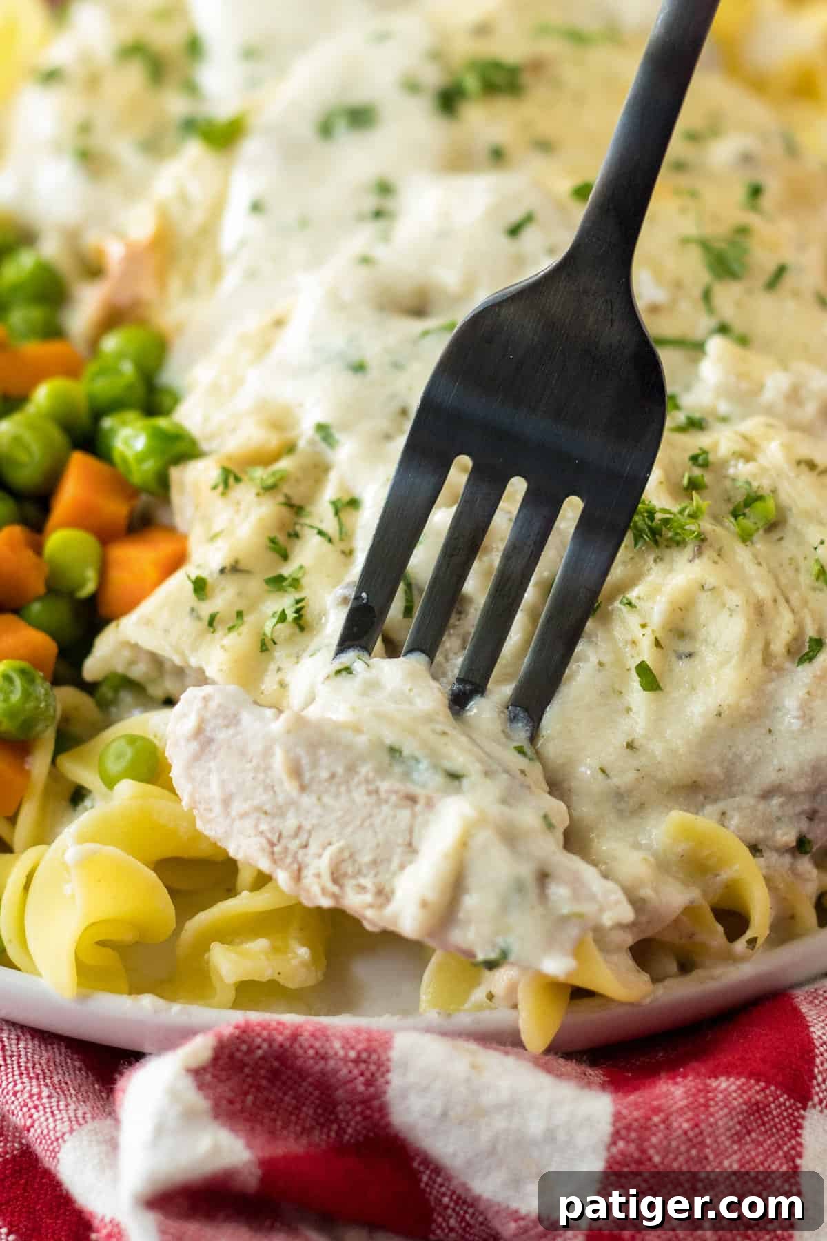 Effortless 4-Ingredient Oven Baked Pork Chops 7 Form taking piece of baked pork chops with creamy sauce.