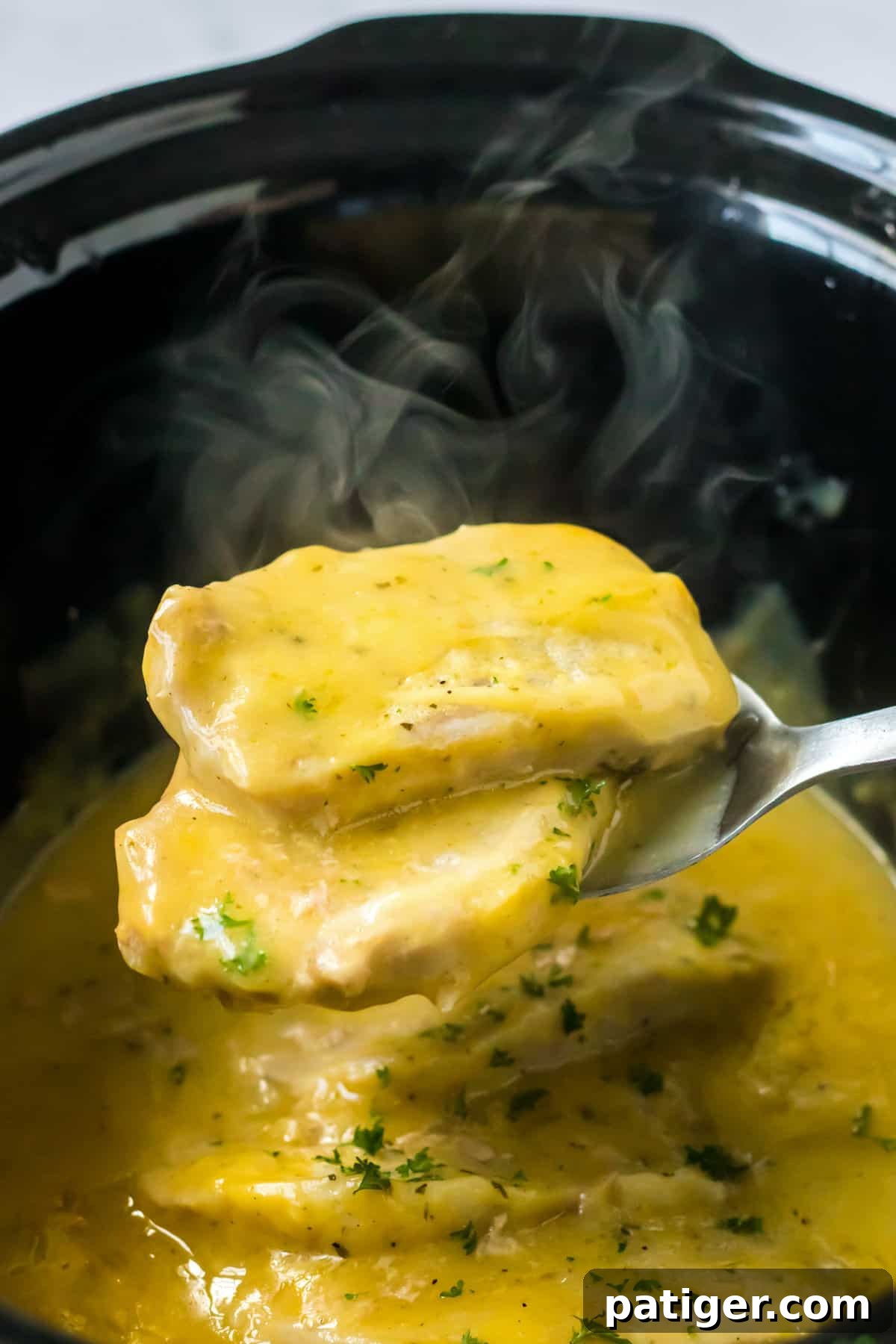 Melt-in-Your-Mouth Slow Cooker Ranch Pork Chops 6 Steaming hot ranch pork chops being removed from the crock pot.