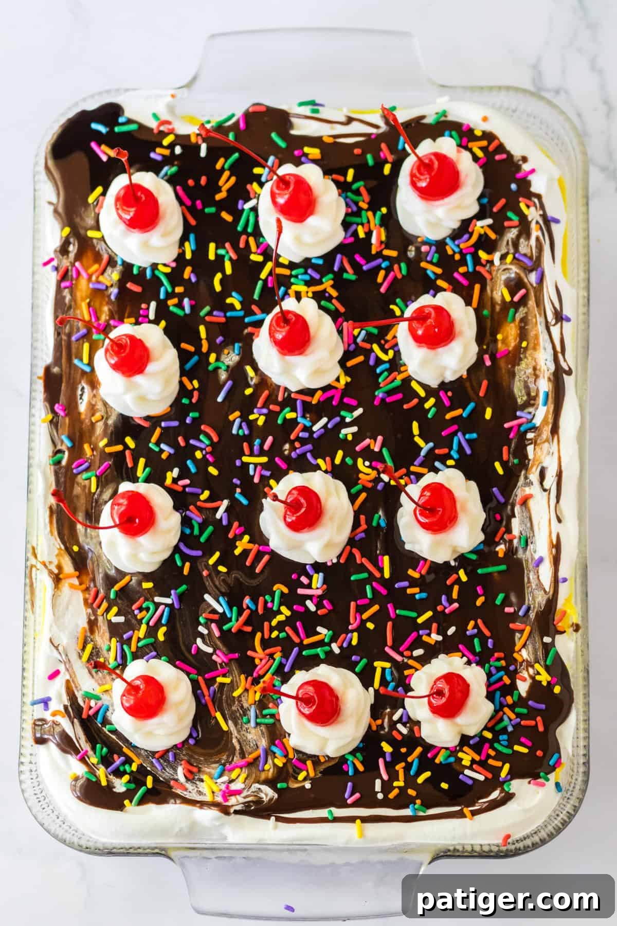 Dessert topped with chocolate syrup, rainbow sprinkles, and 12 dollops of whipped cream each topped with maraschino cherries.