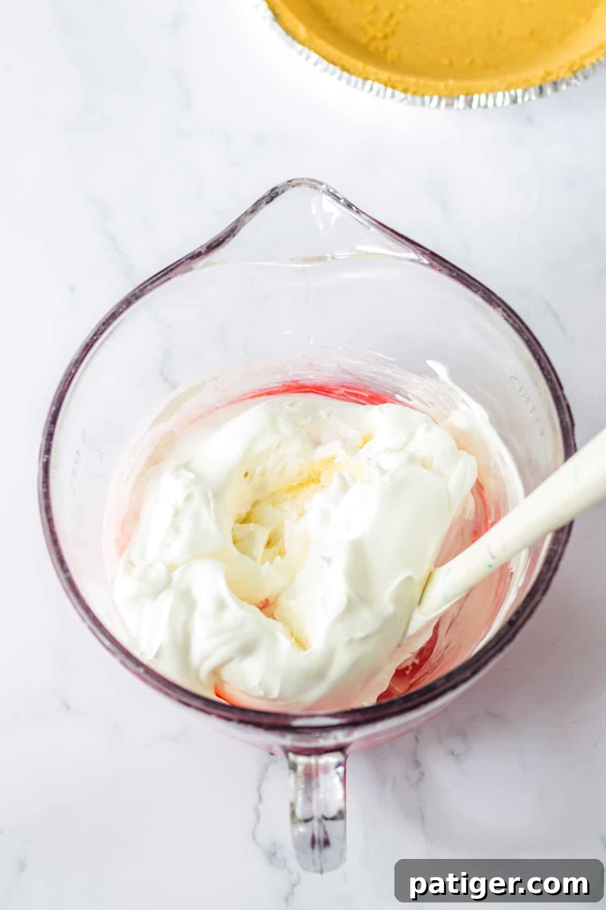 Summer Sip Pie 6 A mixing bowl with the vibrant Kool-Aid mixture, now combined with fluffy Cool Whip, ready to be gently folded in.
