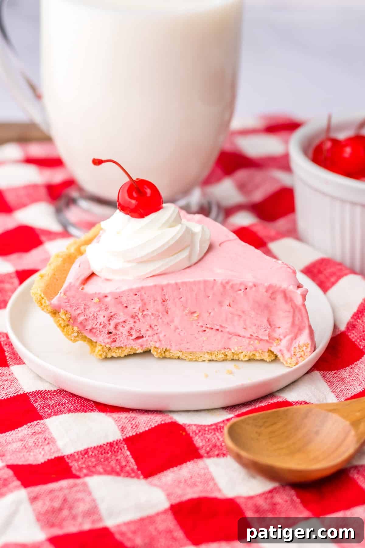Summer Sip Pie 10 A delightful slice of cherry Kool-Aid pie presented on a white plate, with a tall glass of milk in the soft-focus background, inviting enjoyment.