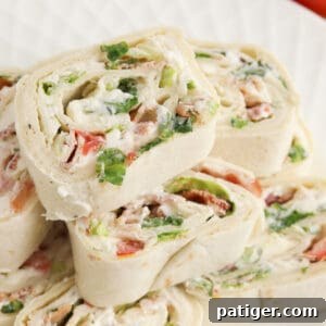 Ranch BLT Pinwheels made with flour tortillas, bacon, lettuce, tomatoes, and ranch dressing stacked on a white plate. A perfect representation of the BLT pinwheel recipe.