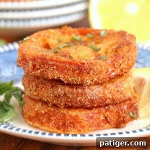 Fried red tomatoes with fresh basil garnish and served with lemon wedge.