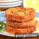 Fried red tomatoes with fresh basil garnish and served with lemon wedge.