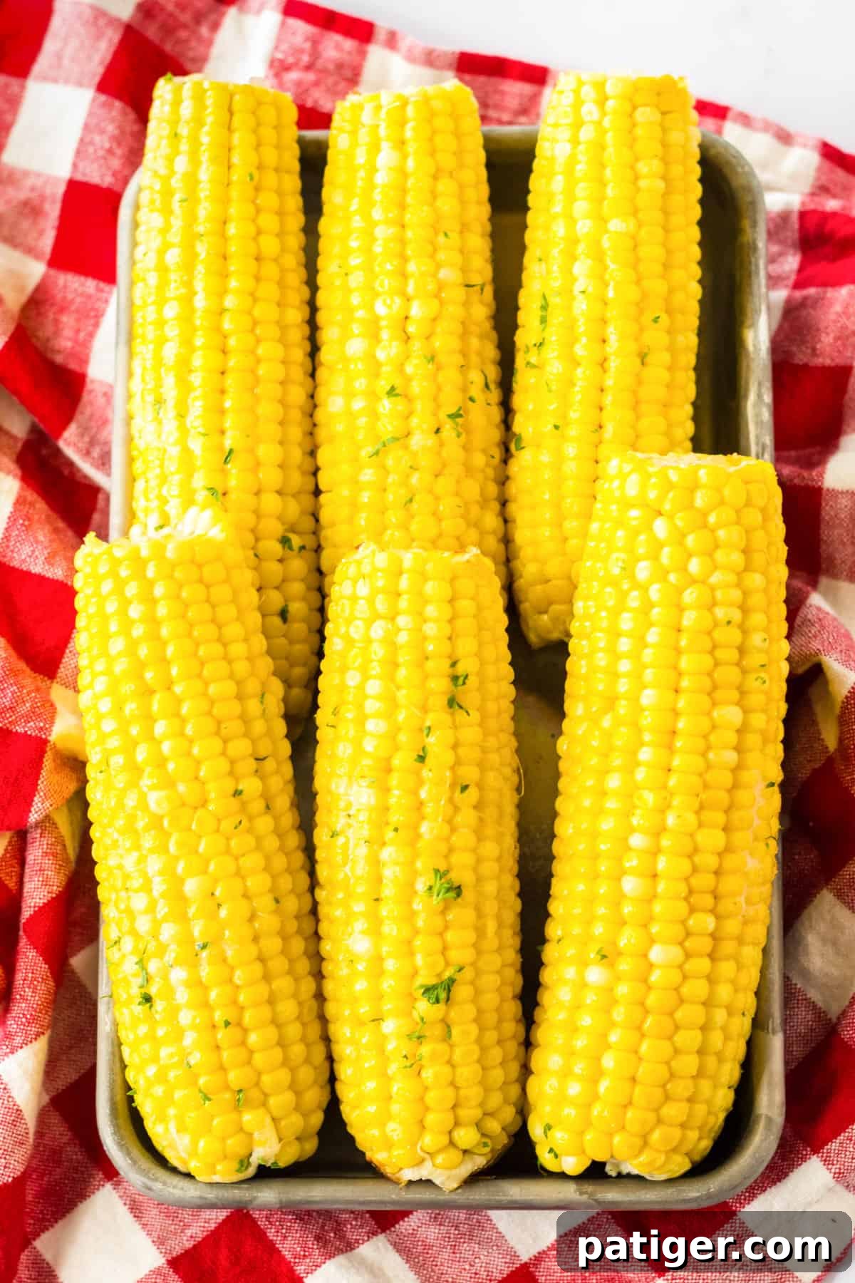 Set It and Forget It Corn on the Cob 8 Seven perfectly slow-cooked corn on the cob arranged on a rustic metal serving tray, ready to be enjoyed.