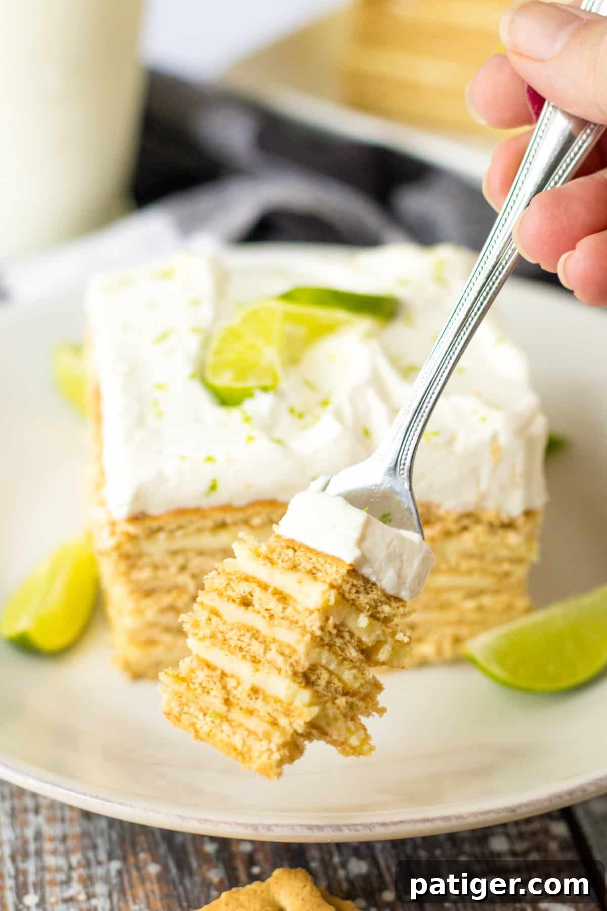 Fork removing a piece from a slice of no bake key lime cake, showing the soft layers.