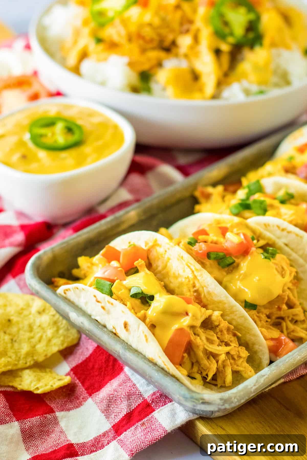 Tempting slow cooker queso chicken tacos nestled in soft flour tortillas, ready to be served on a rustic wooden tray.