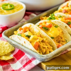 Slow cooker queso chicken tacos served on a tray.