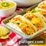 Slow cooker queso chicken tacos served on a tray.