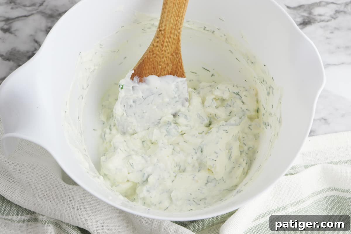 Zesty Dill Cream Cheese Dip 5 Dill dip in a bowl with a wooden spoon.