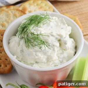 Zesty Dill Cream Cheese Dip 8 Cream cheese dill dip garnished with fresh dill sprig and served with veggie sticks and crackers for dipping.