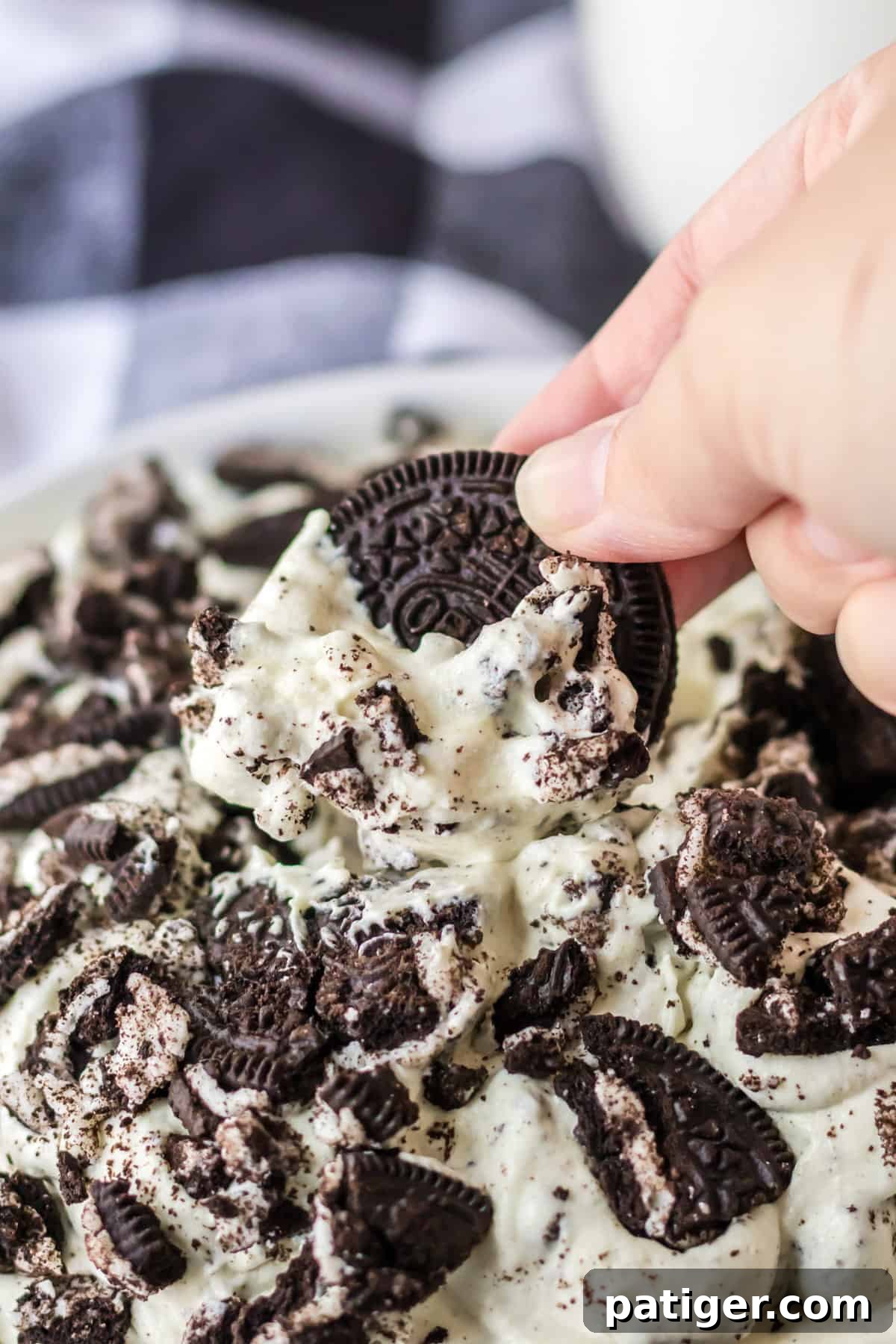 A classic Oreo cookie being dipped into a bowl of creamy Oreo Fluff dip, showcasing its texture.
