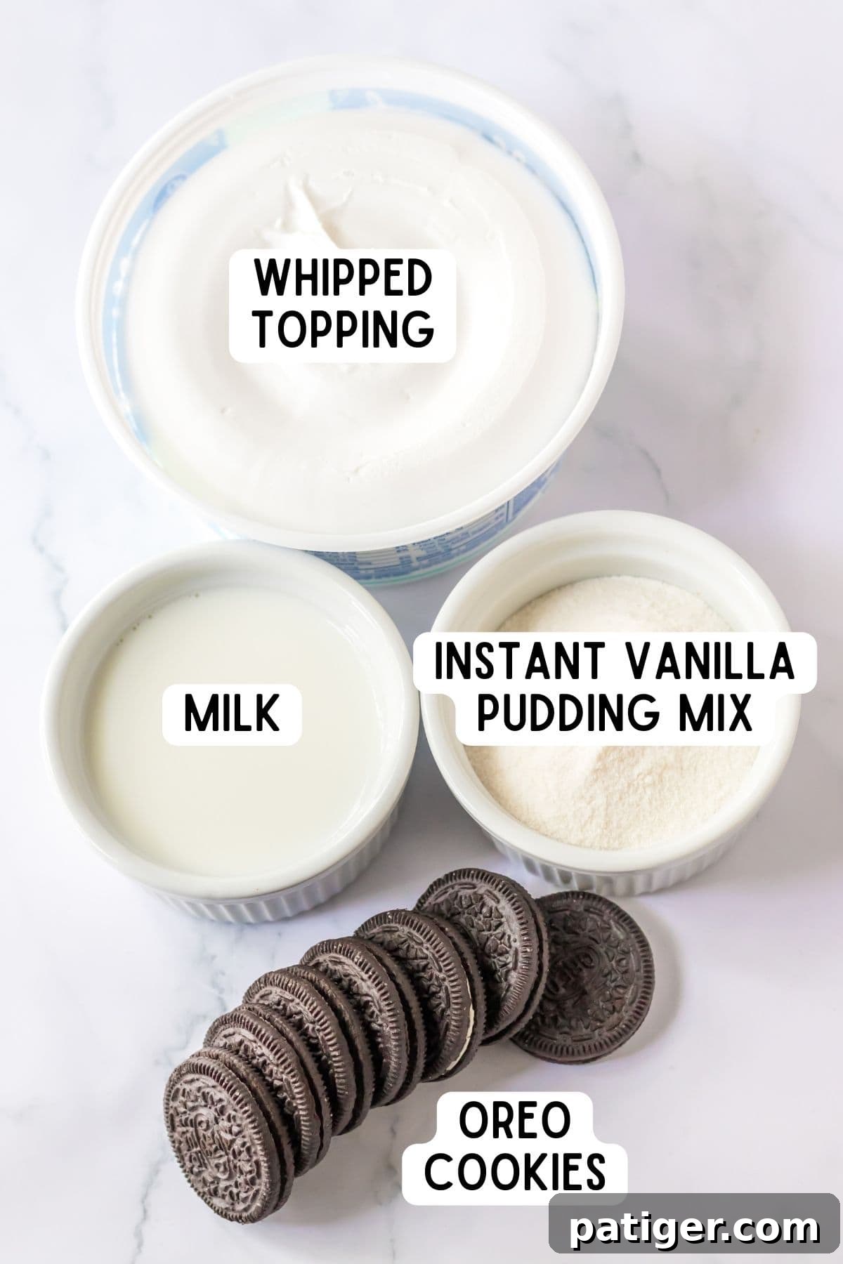 Arrangement of ingredients for Oreo Fluff: whipped topping, milk, instant vanilla pudding mix, and Oreo cookies.