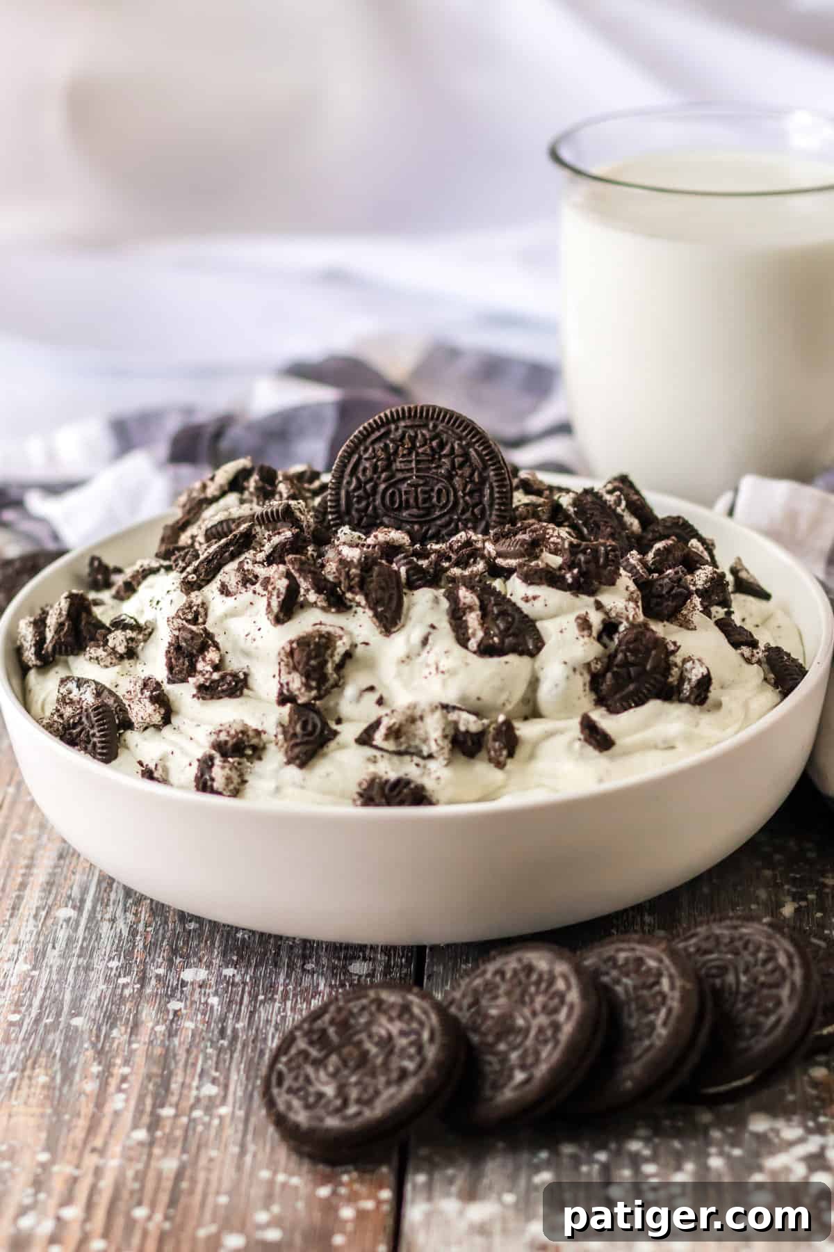 Oreo fluff salad served in a glass bowl, garnished with whole Oreo cookies and accompanied by a glass of milk.