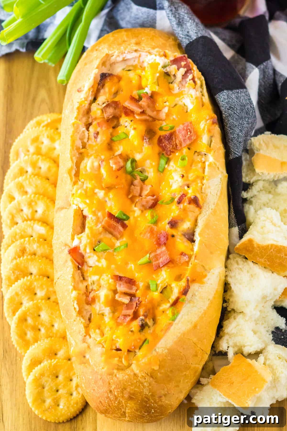 Mississippi Sin Dip with bacon, cheese, and scallions in a bread bowl, served with crackers and bread pieces for dipping.