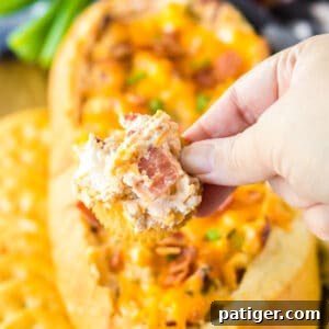 Hand holding a ritz cracker dipped in creamy mississippi sin dip with bacon.